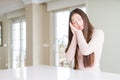 Beautiful Asian woman wearing casual sweater on white table sleeping tired dreaming and posing with hands together while smiling Royalty Free Stock Photo