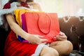 Beautiful asian woman wearing hat and red Santa Claus outfit,sitting on brown leather sofa,enjoy shopping online with tablet, Royalty Free Stock Photo