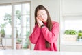 Beautiful Asian woman wearing pink sweater on white table sleeping tired dreaming and posing with hands together while smiling Royalty Free Stock Photo