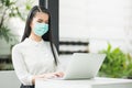 Beautiful asian woman wearing protection mask work from home in the morning. Young asian female with laptop stay at home Royalty Free Stock Photo