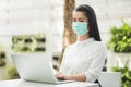 Beautiful asian woman wearing protection mask work from home in the morning. Young asian female with laptop stay at home Royalty Free Stock Photo