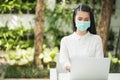 Beautiful asian woman wearing protection mask work from home in the morning. Young asian female with laptop stay at home Royalty Free Stock Photo