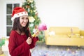 Beautiful asian woman wearing a Santa Claus hat smiling happily on Christmas tree background Royalty Free Stock Photo