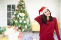 Beautiful asian woman wearing a Santa Claus hat smiling happily on Christmas tree background Royalty Free Stock Photo