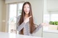 Beautiful Asian woman wearing stripes sweater amazed and smiling to the camera while presenting with hand and pointing with finger Royalty Free Stock Photo