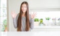 Beautiful Asian woman wearing stripes sweater showing and pointing up with fingers number ten while smiling confident and happy