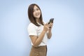 Beautiful Asian woman wearing white t-shirt holding smart phone isolated on blue background. with clipping paths Royalty Free Stock Photo