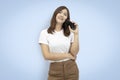 Beautiful Asian woman wearing white t-shirt holding smart phone isolated on blue background. with clipping paths Royalty Free Stock Photo