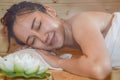 A beautiful asian woman wearing a white towel takes a sauna. The sauna is made of wood with a large. Women in wellness spa