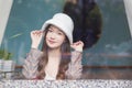 Beautiful Asian woman wears a white hat and plaid coat while she sitting near glassed window in New Year and winter theme Royalty Free Stock Photo