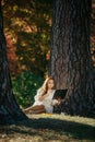 Beautiful asian woman in white dress sit under the tree  writing and thinking in the park with autumn leaves Royalty Free Stock Photo