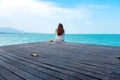 Woman on white dress sitting and looking at the sea and blue sky on wooden balcony with feeling relaxed Royalty Free Stock Photo