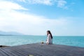 A beautiful asian woman on white dress sitting at the terrace with sea and blue sky background Royalty Free Stock Photo