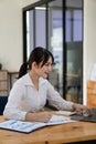 Beautiful Asian woman working on laptop in the office about finance with business report and accounting calculator concept. Charts Royalty Free Stock Photo