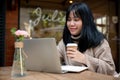 A beautiful Asian woman is working remotely at a cafe in the city, working on her laptop Royalty Free Stock Photo