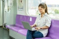 Beautiful asian woman working urgently on a laptop computer at the .electric train in the morning