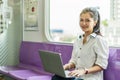 Beautiful asian woman working urgently on a laptop computer at the .electric train in the morning