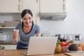 Beautiful Asian woman in workout clothes searches for healthy recipes online on her laptop. while preparing healthy food Royalty Free Stock Photo