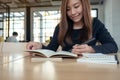 A beautiful asian woman writing on blank notebook on table in cafe Royalty Free Stock Photo