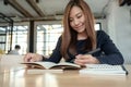 A beautiful asian woman writing on blank notebook on table in cafe Royalty Free Stock Photo