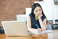 Beautiful Asian woman writing a notebook on table with laptop as Royalty Free Stock Photo