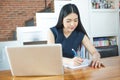 Beautiful Asian woman writing a notebook on table with laptop aside. Royalty Free Stock Photo