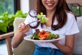Beautiful Asian women are enjoying eating salad with salmon to lose weight. Healthy young woman eating vegetable salad. Dieting , Royalty Free Stock Photo