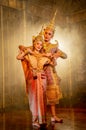 Beautiful Asian woman wear Thai traditional dress action of dancing together with man stand in front of Thai painting on public Royalty Free Stock Photo