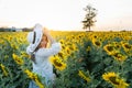 A beautiful asian women in a white dress and hat walking on a field of sunflowers , smiling a beautiful smile,cheerful girl,style Royalty Free Stock Photo