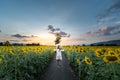 A beautiful asian women in a white dress and hat walking on a field of sunflowers , smiling a beautiful smile,cheerful girl,style Royalty Free Stock Photo