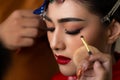 Beautiful asian young bride apply beautiful makeup and hairdo by makeup artist, hairstylist for wedding ceremony. Attractive asian Royalty Free Stock Photo