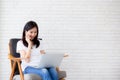 Beautiful asian young businesswoman excited and glad of success with laptop, girl taking mobile phone and working Royalty Free Stock Photo