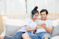 Beautiful asian young couple listening to music with tablet on bed. Royalty Free Stock Photo