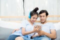 Beautiful asian young couple listening to music with tablet on bed. Royalty Free Stock Photo