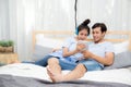 Beautiful asian young couple listening to music with tablet on bed. Royalty Free Stock Photo