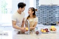 Beautiful asian young couple is looking to cooking in kitchen at Royalty Free Stock Photo