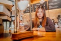 Asian young female is sitting before a hourglass counting down with smile for relaxing time concept