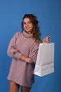 Beautiful asian young irl holding a white blank paper bag and makes purchases in an online store against a black wall background Royalty Free Stock Photo