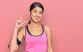 Beautiful asian young sport woman wearing sportswear and arm band smiling and confident gesturing with hand doing small size sign Royalty Free Stock Photo