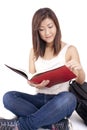 Beautiful Asian young woman with backpack reading red book