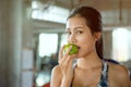 Beautiful Asian young woman eat green apple in fitness gym . healthy eating lifestyle . nutritious . sport . workout. training . Royalty Free Stock Photo