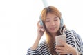 Beautiful asian young woman enjoy listen music with headphone and holding smart mobile phone Royalty Free Stock Photo