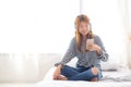 Beautiful asian young woman enjoy listen music with headphone and holding smart mobile phone while sitting in bedroom Royalty Free Stock Photo