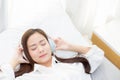 Beautiful asian young woman enjoy listen music with headphone while lying in bedroom. Royalty Free Stock Photo