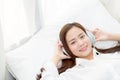 Beautiful asian young woman enjoy listen music with headphone while lying in bedroom. Royalty Free Stock Photo