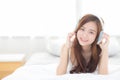 Beautiful asian young woman enjoy listen music with headphone while lying in bedroom Royalty Free Stock Photo