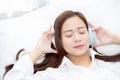 Beautiful asian young woman enjoy listen music with headphone while lying in bedroom Royalty Free Stock Photo