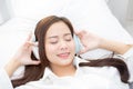 Beautiful asian young woman enjoy listen music with headphone while lying in bedroom Royalty Free Stock Photo