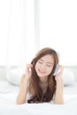 Beautiful asian young woman enjoy listen music with headphone while lying in bedroom. Royalty Free Stock Photo