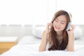 Beautiful asian young woman enjoy listen music with headphone while lying in bedroom Royalty Free Stock Photo